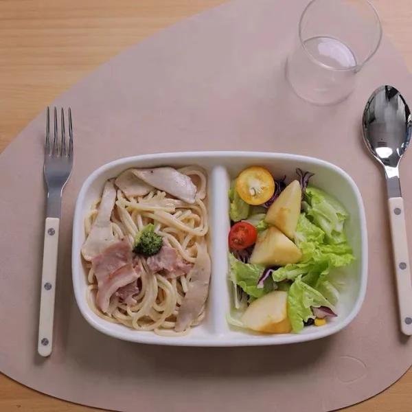 Studio M' Aeroport 雙格盤裝着沙律放在枱上，兩邊各放了一把叉與匙羹的俯視圖。