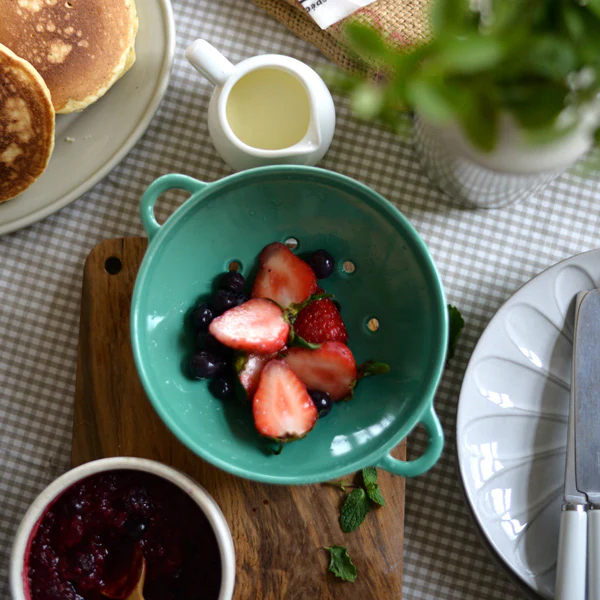 薄荷綠款 Studio M’ Berry 雙耳瀝水碗裝着草莓放在一塊木板上的俯視圖。