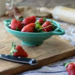 薄荷綠款 Studio M’ Berry 雙耳瀝水碗裝着草莓放在一塊木板上。