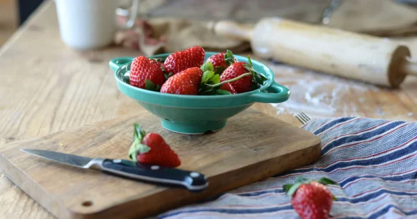 薄荷綠款 Studio M’ Berry 雙耳瀝水碗裝着草莓放在一塊木板上。
