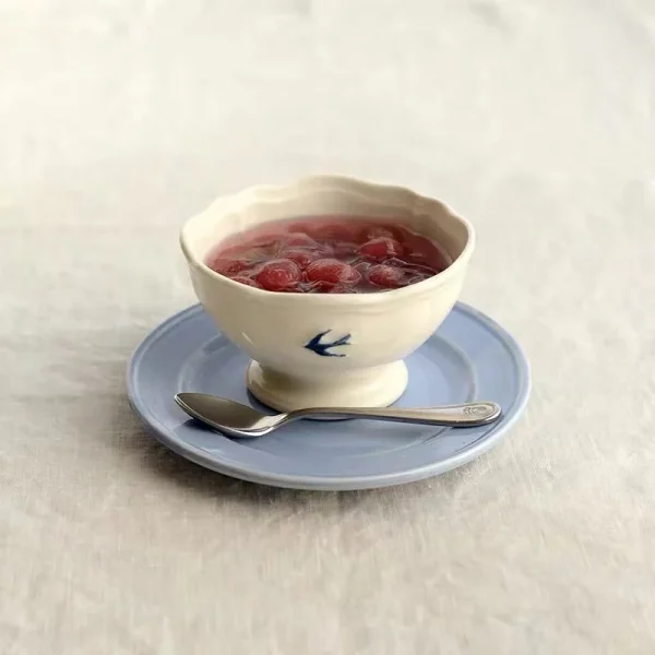 枱上有一個 Studio M' Early Bird 小碗裝着甜品放在圓碟上，碟上還放了小匙羹。