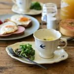 Studio M' Early Bird 燕子系列茶杯裝着食物放在同系列的碟子上，枱上還有其他早餐食物與飲品。