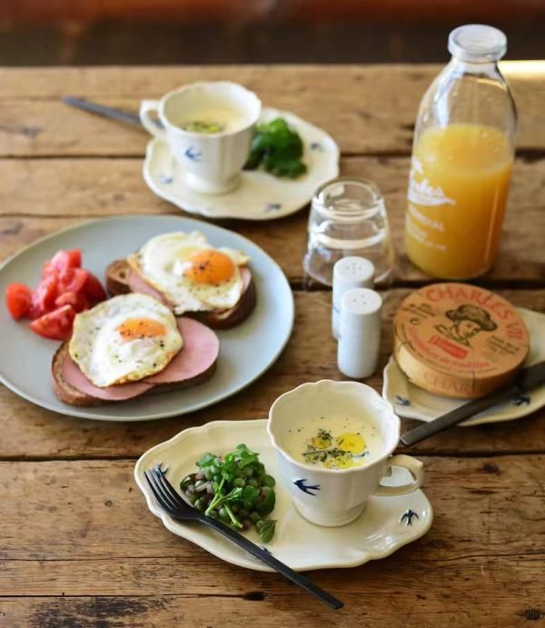 Studio M' Early Bird 燕子系列茶杯裝着食物放在枱面，枱上還有其他早餐食物與飲品。