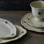不同Studio M' Early Bird 燕子系列的餐碟、茶杯放在木枱上展示邊緣細節。
