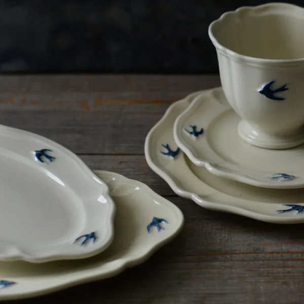 不同Studio M' Early Bird 燕子系列的餐碟、茶杯放在木枱上展示邊緣細節。