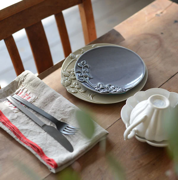 啡色及深灰色款Studio M' MINT 浮雕餐盤疊起放在木枱面,旁邊有刀叉及杯具。