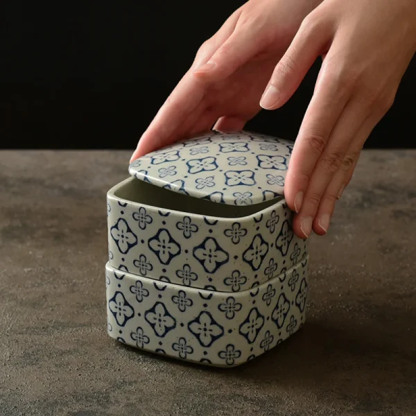 雙手拿起疊起而放的藍色 Studio M' Nobana 野花二段疊盒的蓋子