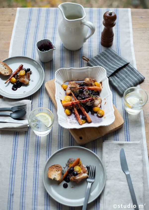 白色款Studio M' Antico 烤盤裝隻食物放在鋪了藍色條紋枱布的枱中間，枱上還有裝了食物的餐碟與其他餐具。