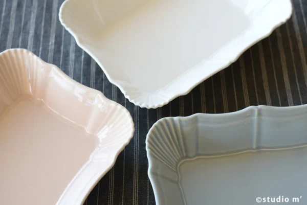 三個不同顏色的 Studio M' Antico 烤盤角對角放在木枱上的邊緣設計特寫俯視圖