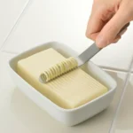 用手拿着吉川不銹鋼牛油刀刮牛油的示範圖