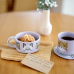 紫色 CDF ètendue I LOVE CAT！貓咪湯碗和紫色貓咪面圖案可堆疊陶瓷杯一起放在餐桌上的放大圖