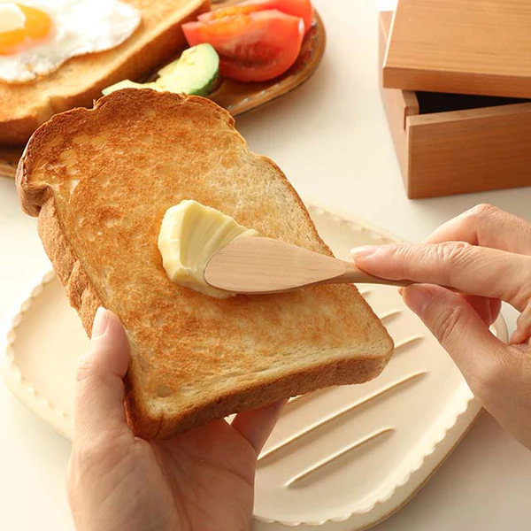 日本製山櫻木牛油盒放在餐桌上,乎正用木匙羹將牛油茶到多士上