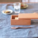 日本製山櫻木牛油盒放桌上,蓋子半打開放在盒上,可見裏面裝着牛油