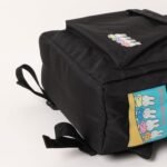 黑色背包上有彩色的Miffy 公仔圖案，靠近底角的貼片上有 Dear Bruna 字樣。主隔間和背帶清晰可見。.